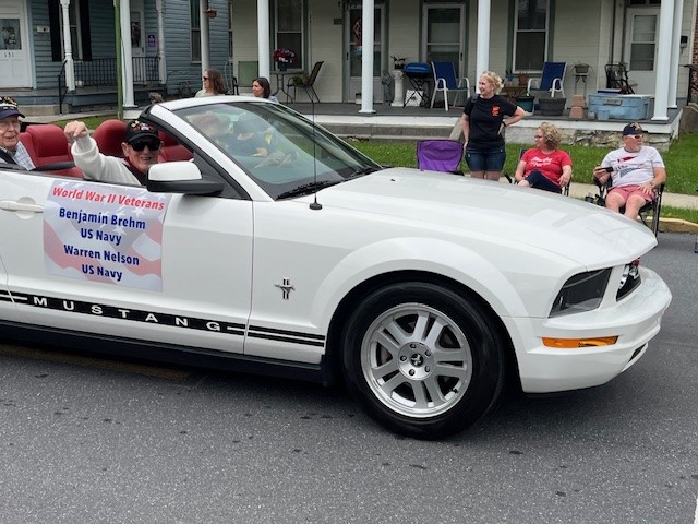 Veterans parading in a convertible car during a community event.