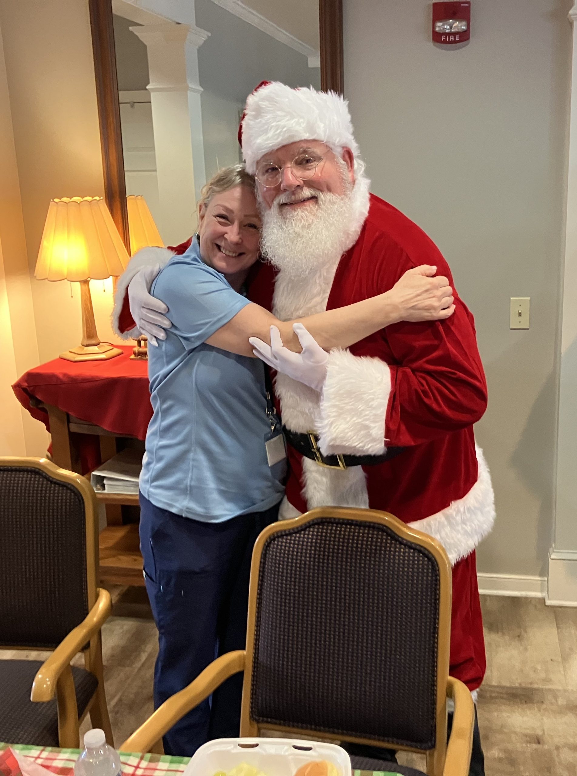 Staff member posing with Santa Claus in a festive setting.