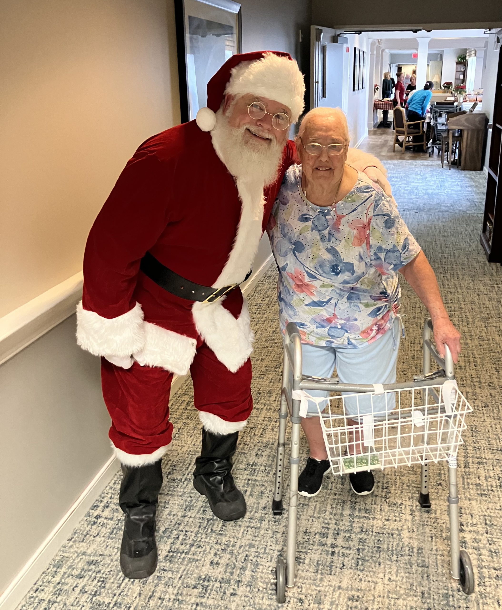Resident posing with Santa in the hallway