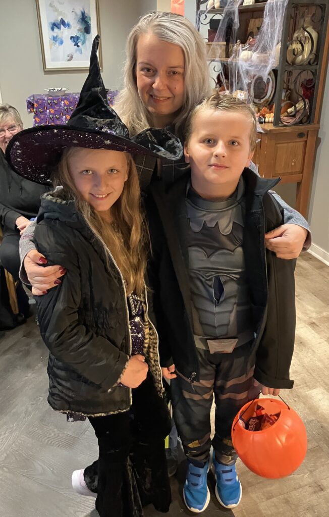 Children in costumes celebrating Halloween with an adult