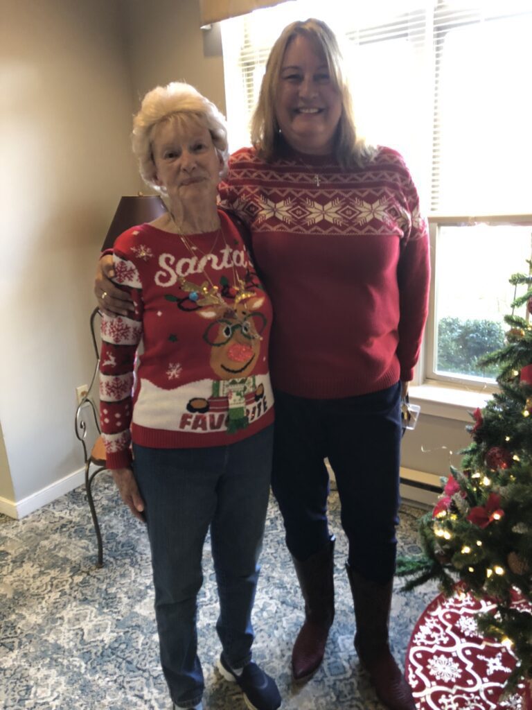 Residents wearing festive sweaters by a Christmas tree