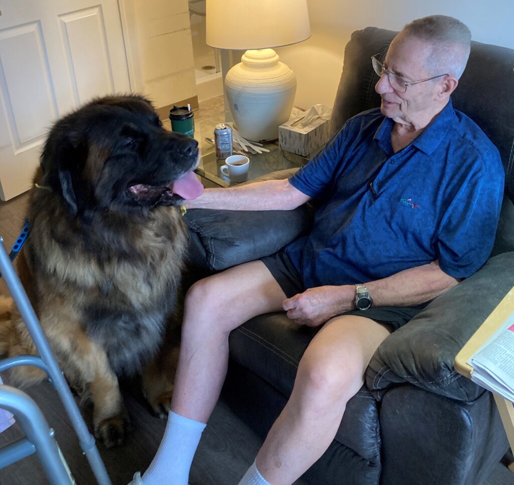 Senior man with a large dog in a cozy chair.