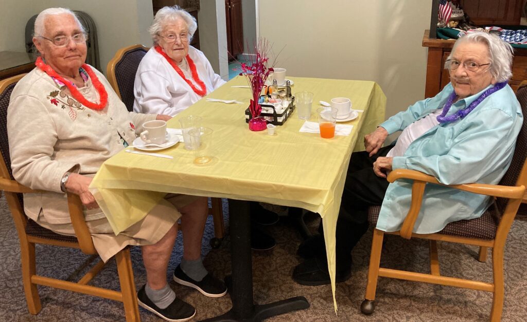 Three residents enjoying tea with leis on