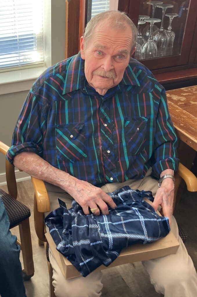 Senior man opening a gift in a warm setting.