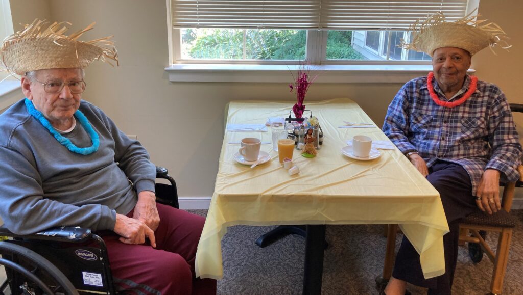 Two residents celebrating with festive hats and snacks.