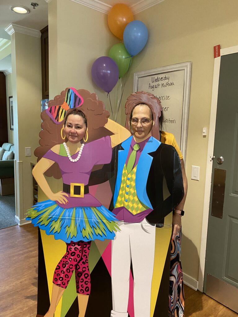 Two residents posing with colorful cutouts in a common area.