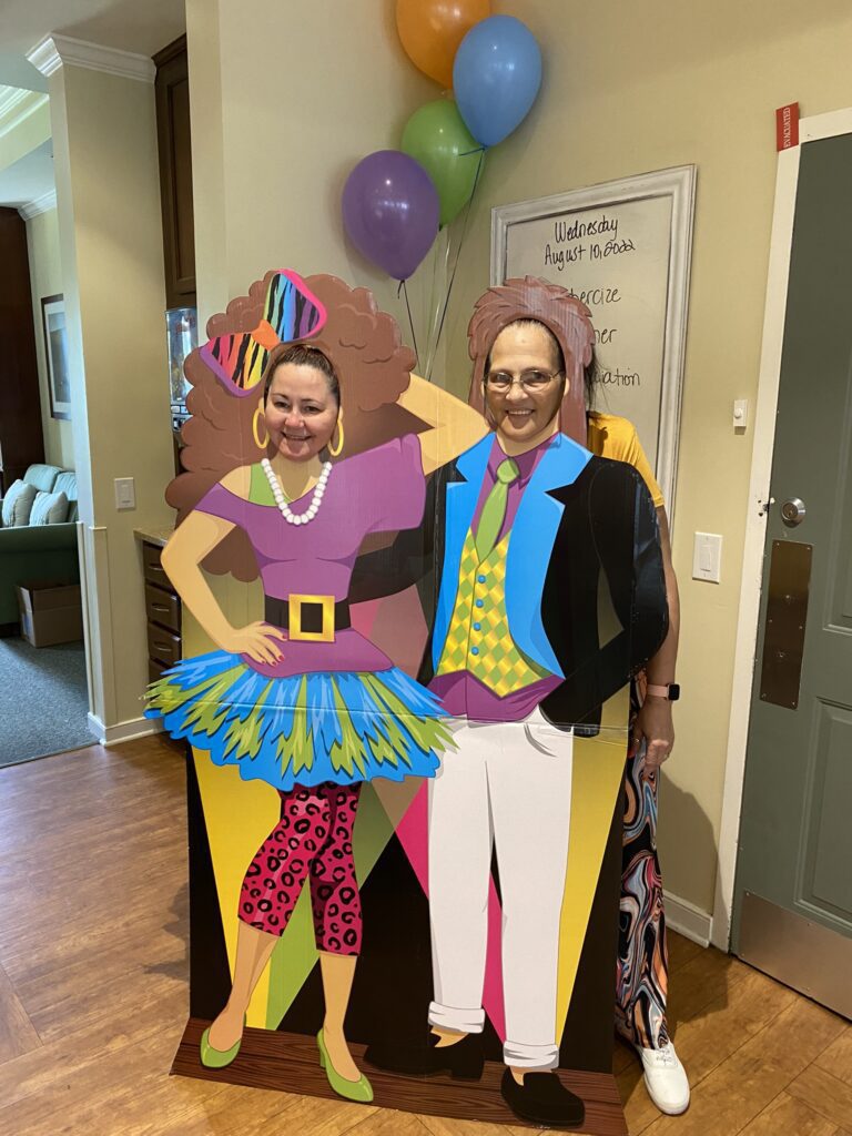 Residents posing with a colorful cutout during an event.