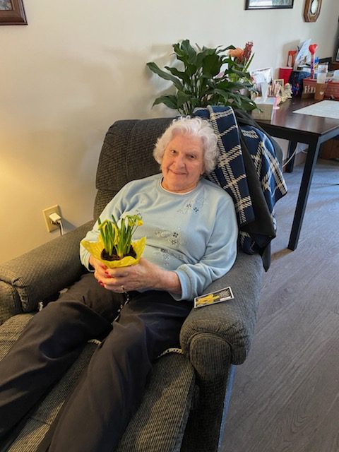 Senior resident holding a potted plant in a cozy chair