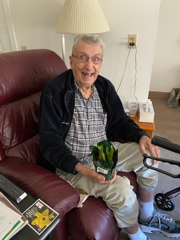 Senior resident enjoying a plant in a cozy chair.