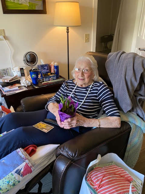 Resident holding a potted plant in a cozy room.