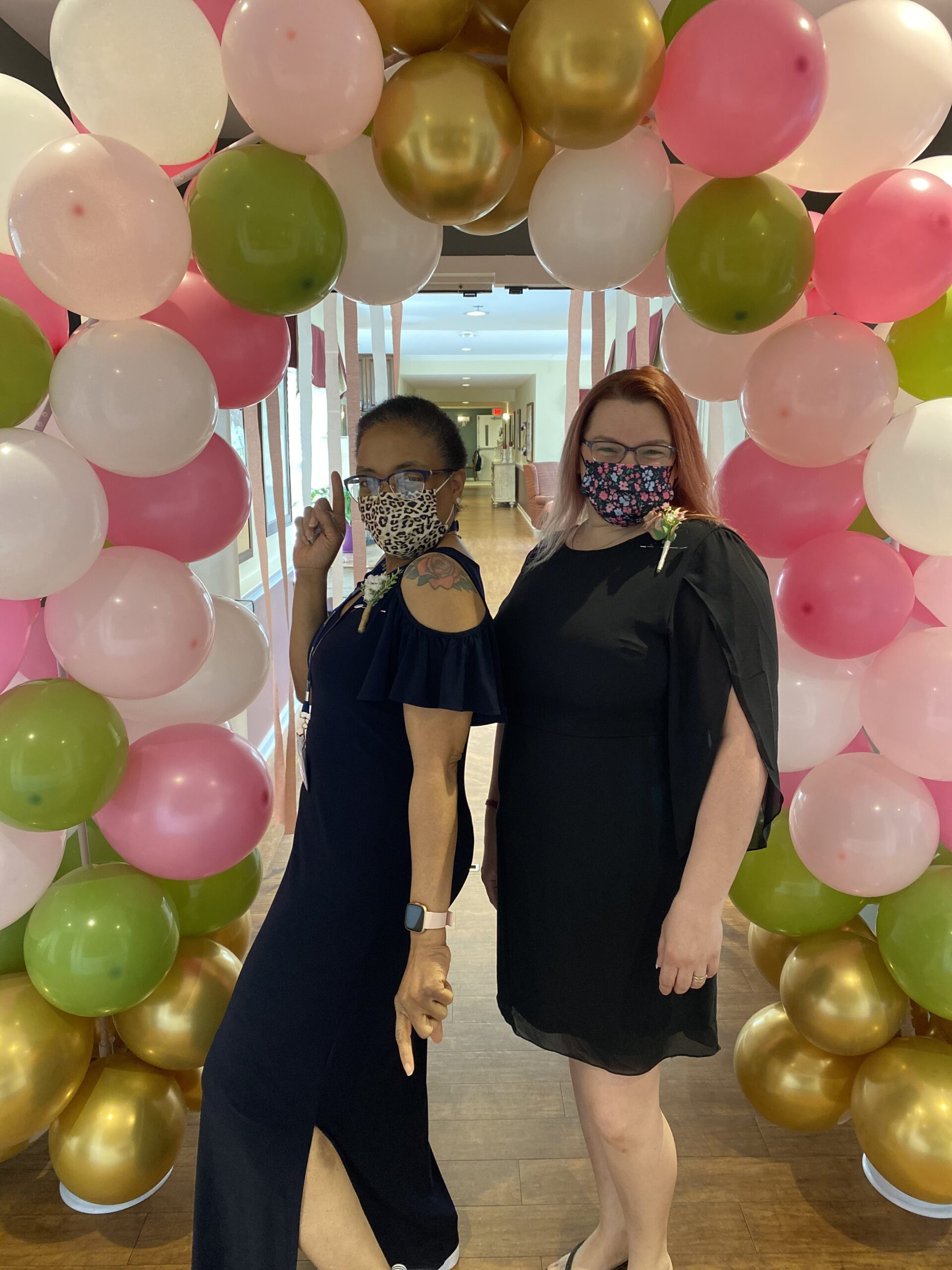 Two women posing in festive attire among balloons
