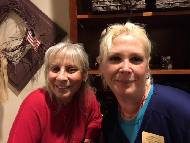 Two staff members smiling together in a facility setting.