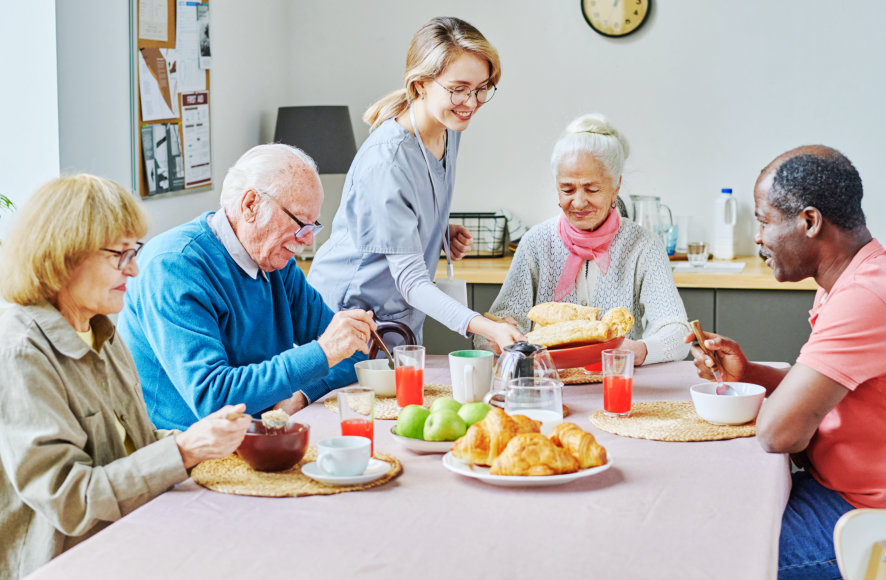 Residents enjoying a meal with staff assistance.