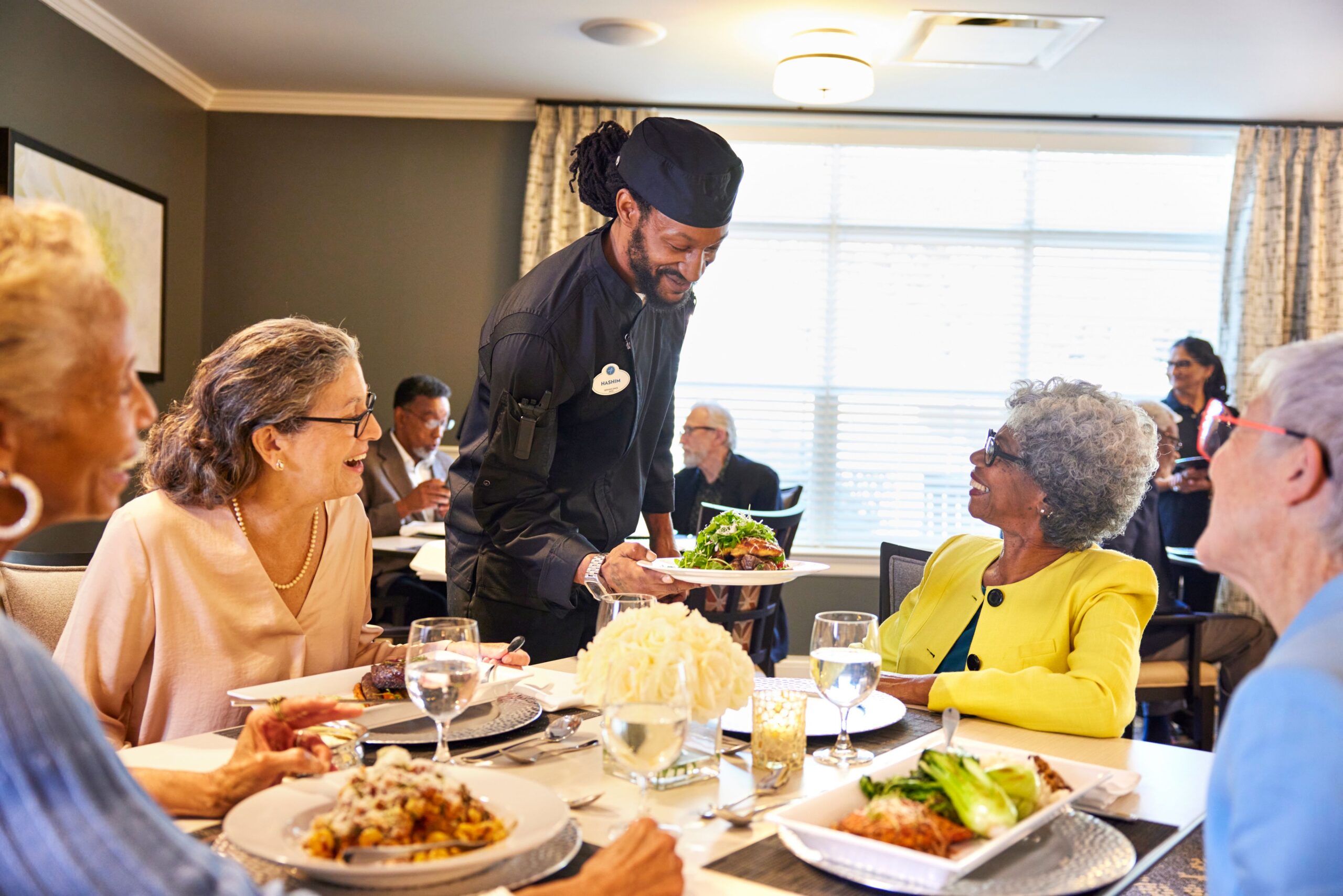 Residents enjoying a meal with staff in a dining area