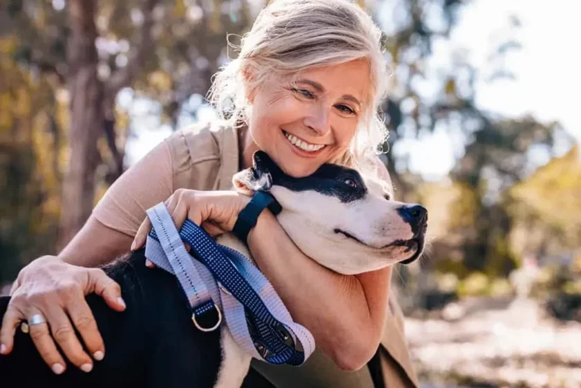 A woman smiling with a dog in a garden