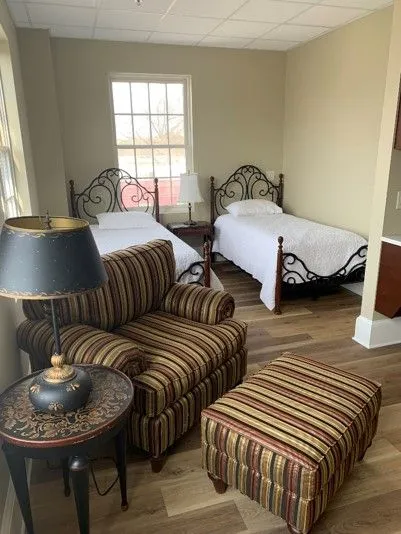 Cozy twin bedroom setup with armchair and lamp