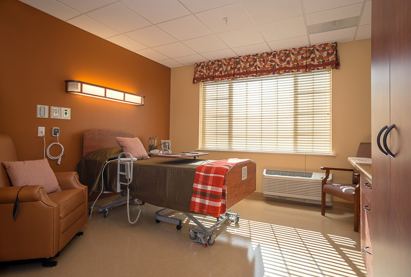 A private resident room with a hospital bed and chair