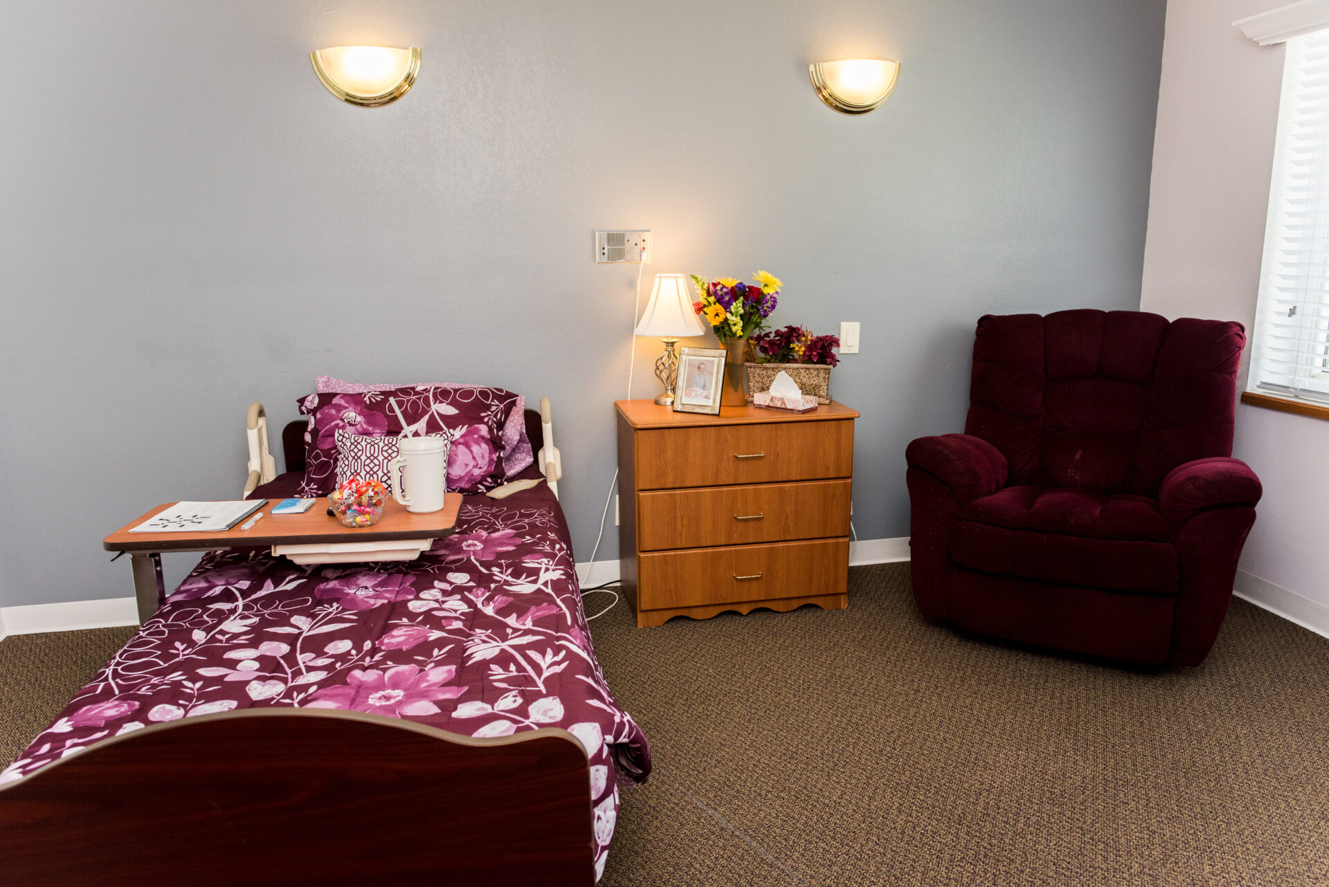 Cozy resident room with bed, chair, and flowers