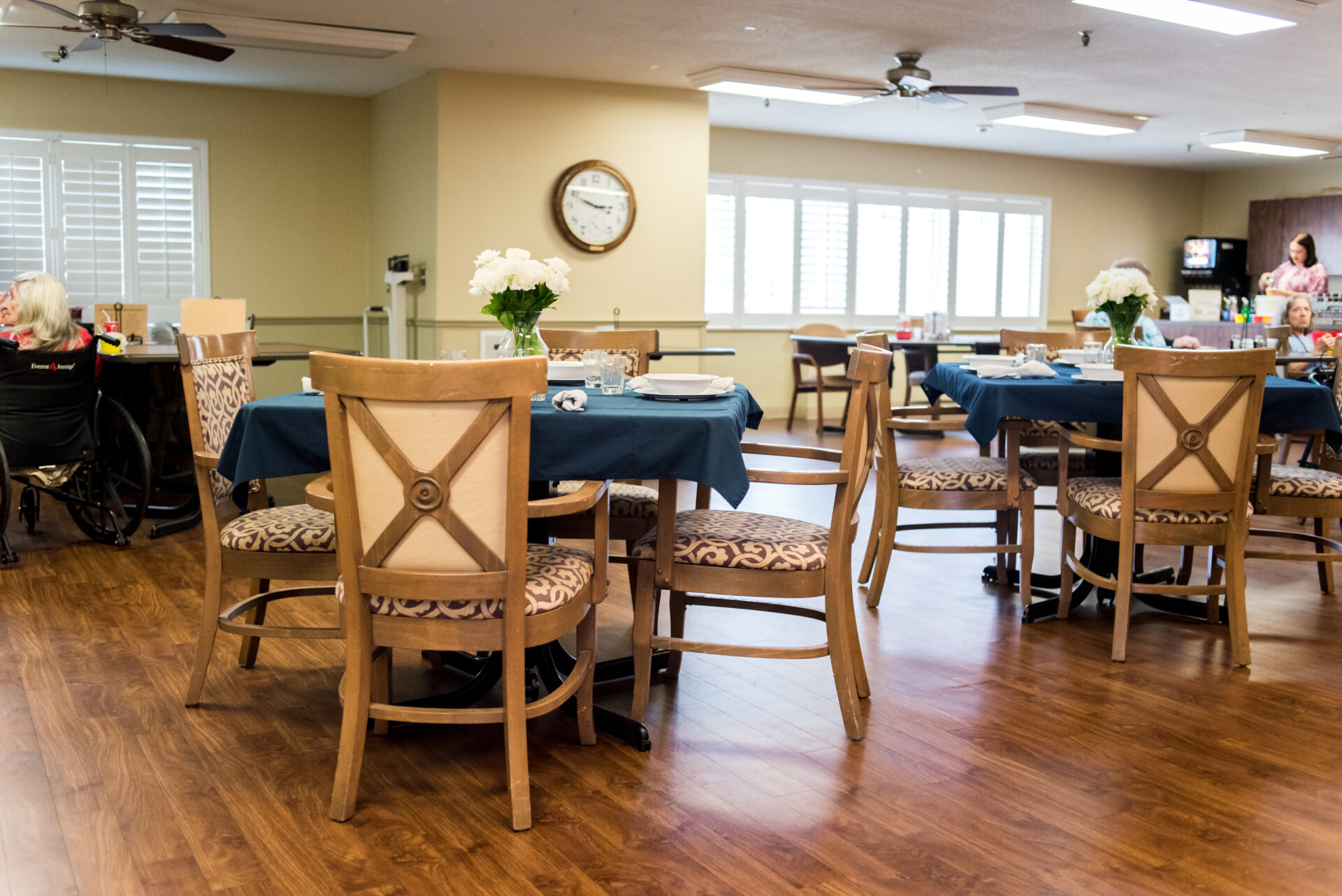 Dining area with residents and tables set for meals