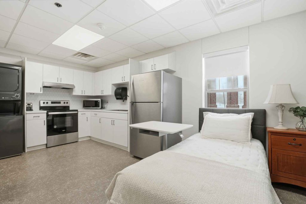A private room with a bed and kitchenette area