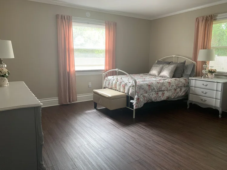 Brightly lit private resident room with floral bedding