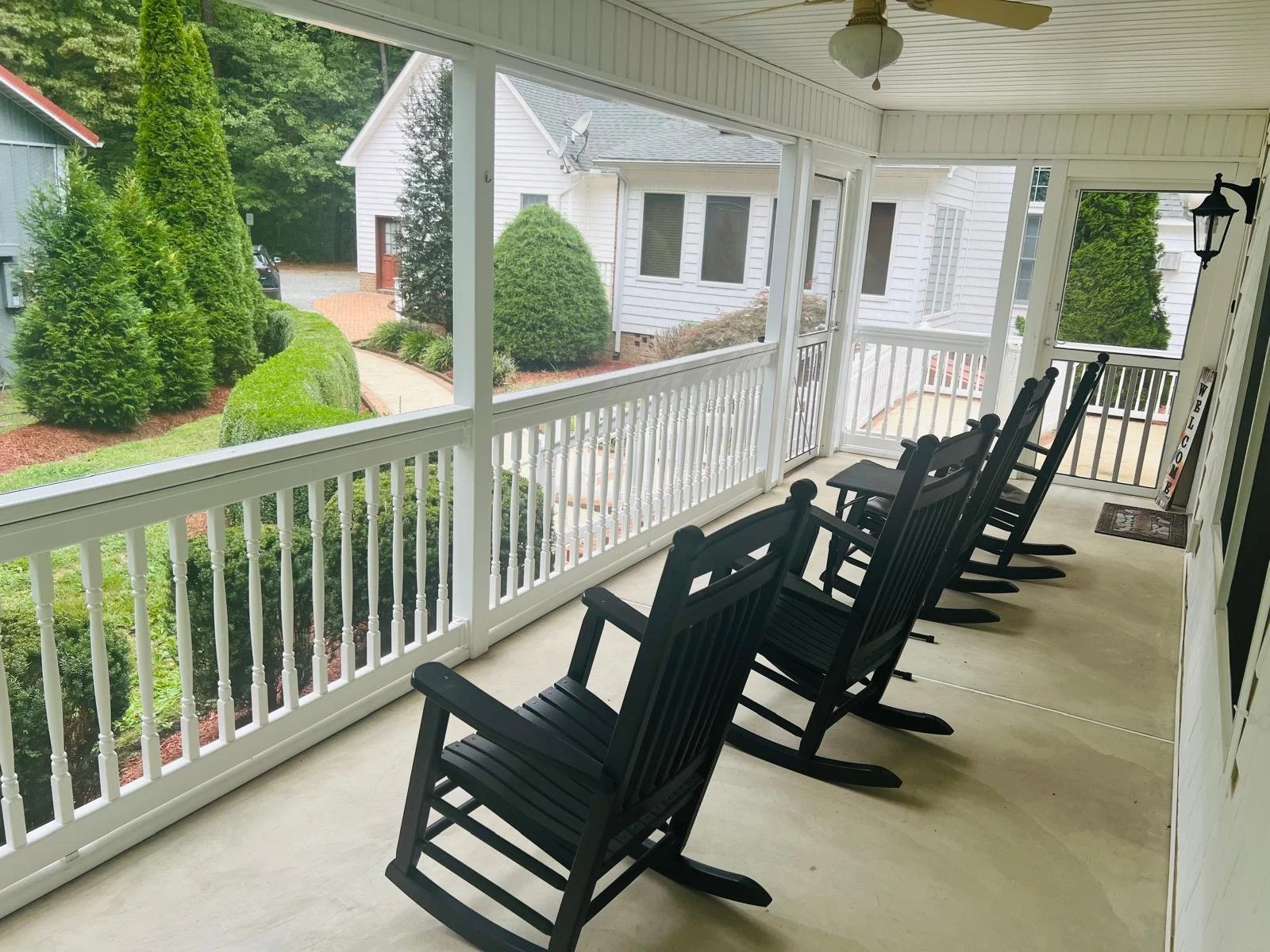 Covered porch with rocking chairs overlooking a green landscape