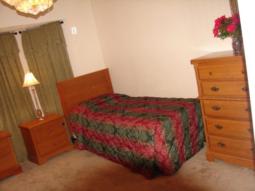 Cozy bedroom with wooden furniture and green curtains.
