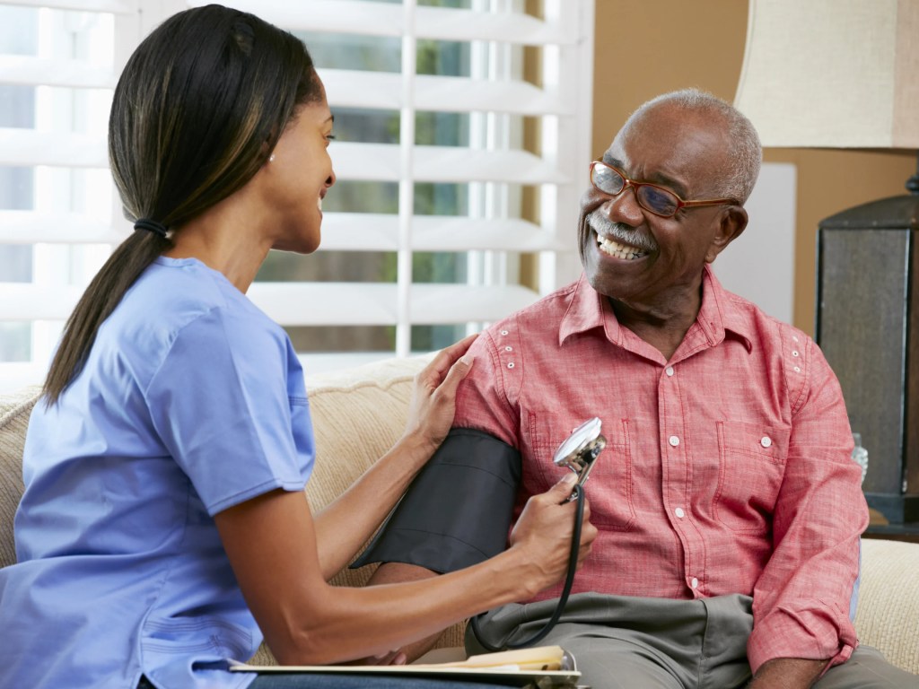 Nurse assisting an elderly man with a checkup.